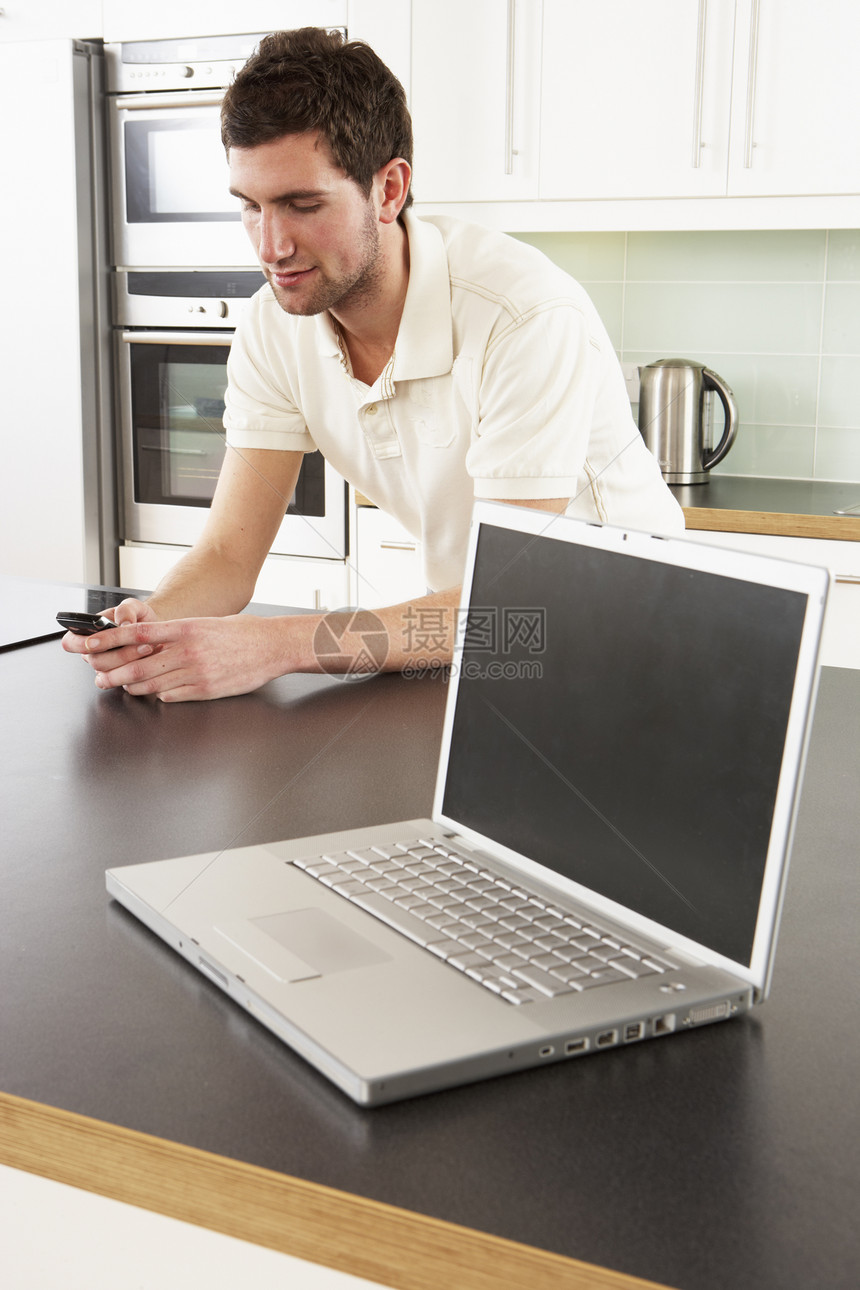 现代厨房用笔记本电脑的年轻人图片
