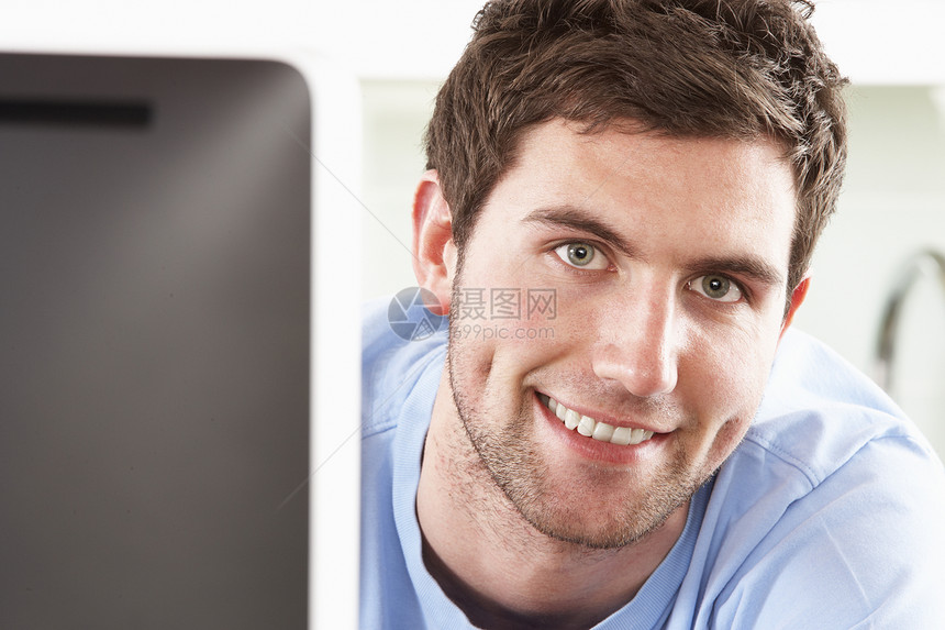 现代厨房使用计算机的青年男子屏幕水平设计师监视器电脑微笑建筑学长度男性居家图片
