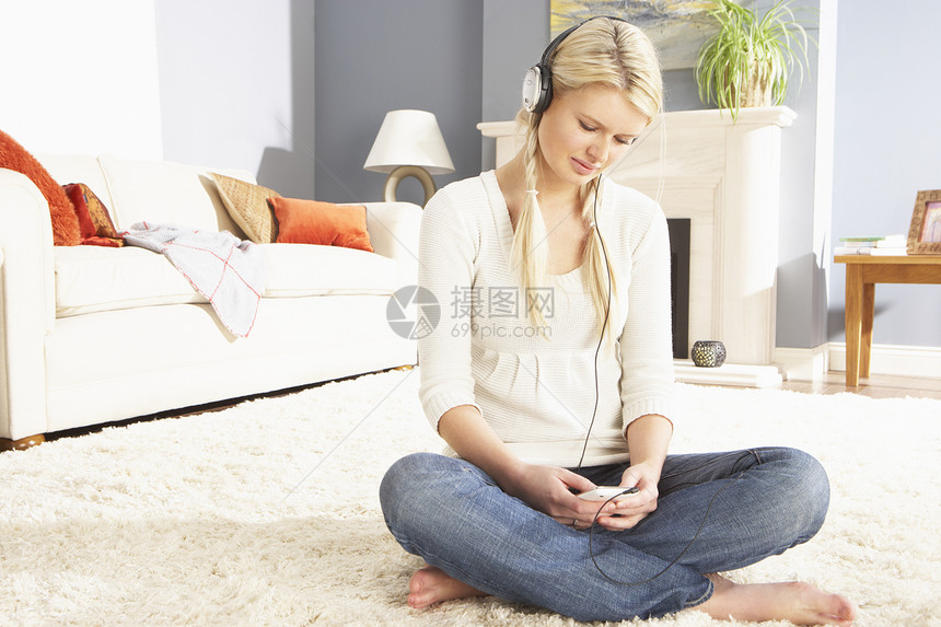 女性在耳机上监听MP3玩家的节目音乐金发女郎娱乐金发水平闲暇小地毯成人微笑客厅图片