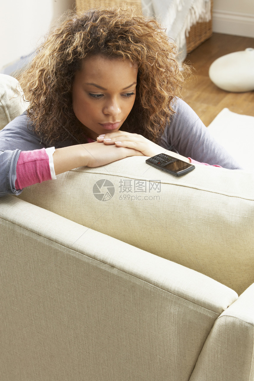在家用手机在SafaWating上坐着的妇女客厅孤独细胞女性电话沙发成人长度图片