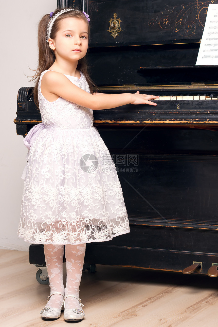 女孩穿着美丽的裙子 在钢琴附近音乐白色爱好女儿学生站立学习乐趣喜悦黑色图片