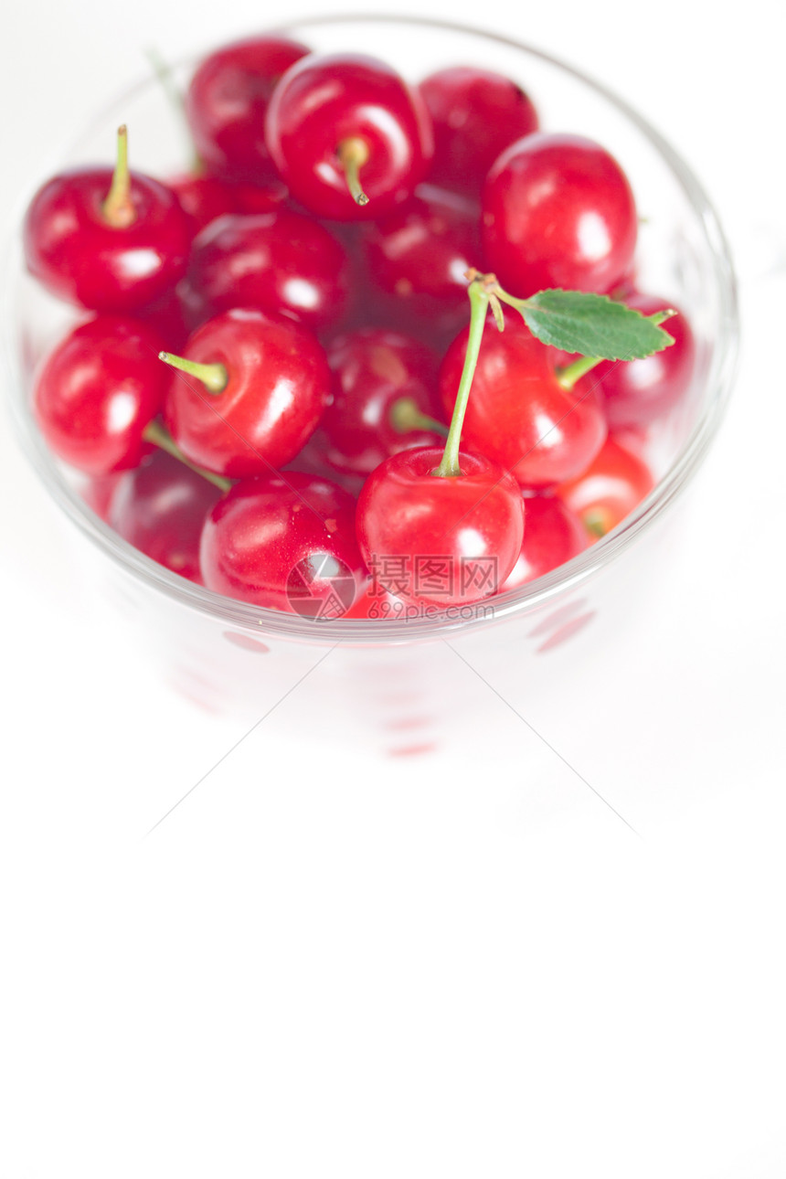 绿色的樱桃叶和白色草原上的樱桃杯甜点宏观盘子美食杯子用具食物水果玻璃工作室图片
