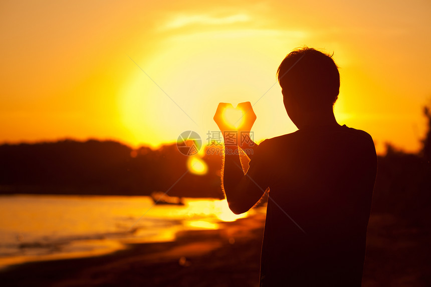 青年男子手握着日落的阳光场景点燃摄影太阳蓝色活力镜片反射男人耀斑图片