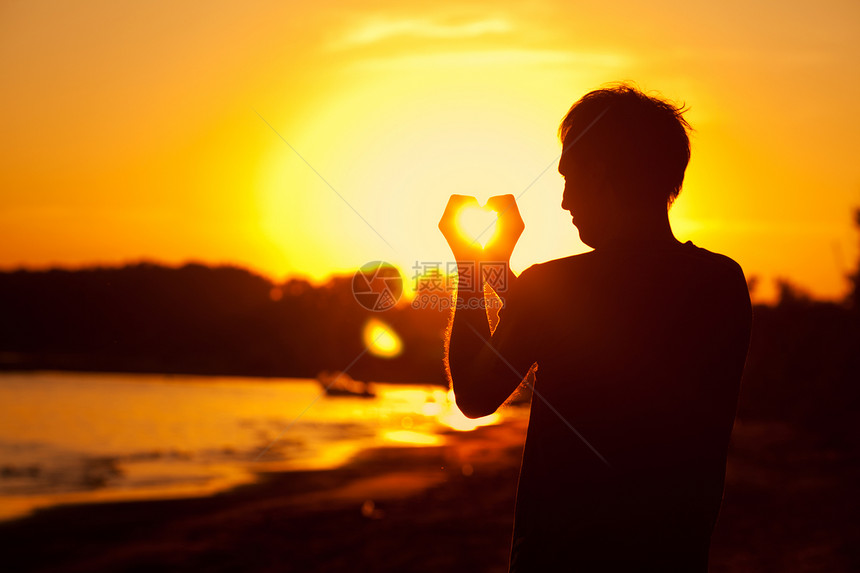 青年男子手握着日落的阳光镜片反射活力点燃蓝色男人沉思天空生活创造力图片