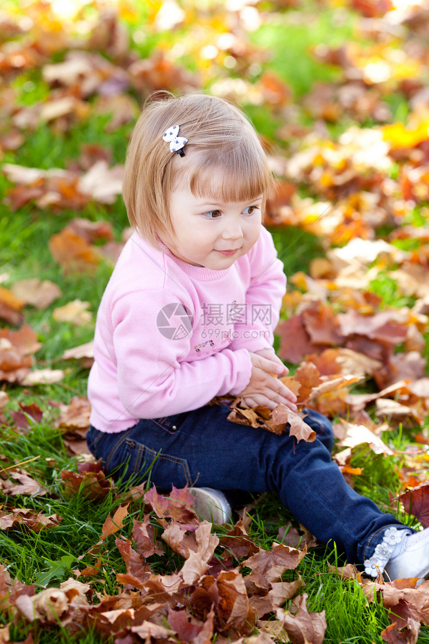美丽的小女孩坐在秋天的树叶上季节压痛微笑女儿红色森林女性叶子童年女孩图片