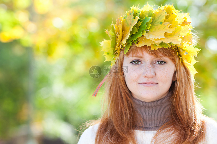 一位美丽的年轻红发女青年 在花圈的肖像微笑公园地面季节女孩喜悦金子青少年乐趣女性图片
