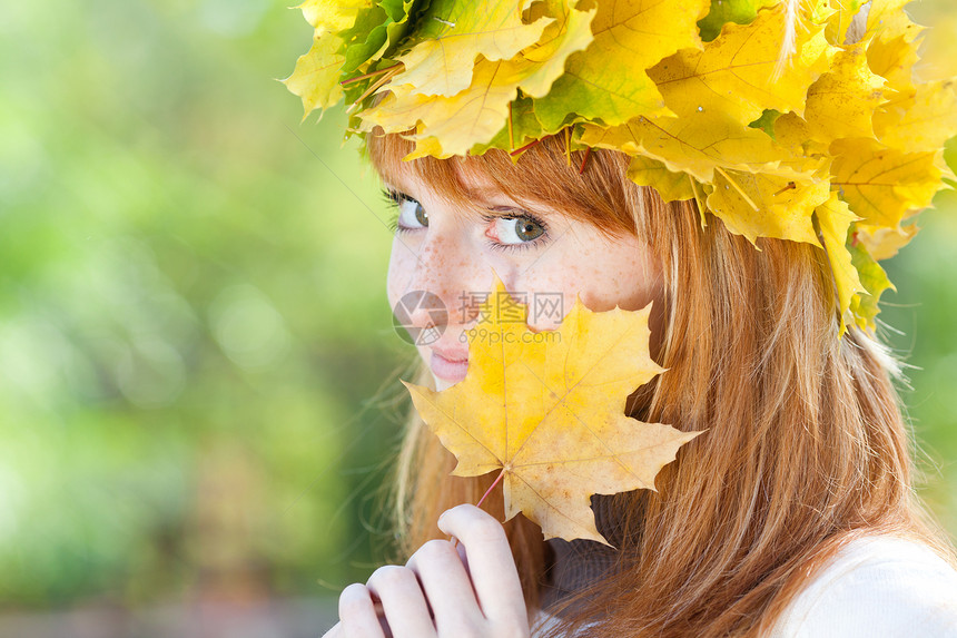 一位美丽的年轻红发女青年 在花圈的肖像喜悦叶子学生地面乐趣女孩幸福金子天气森林图片