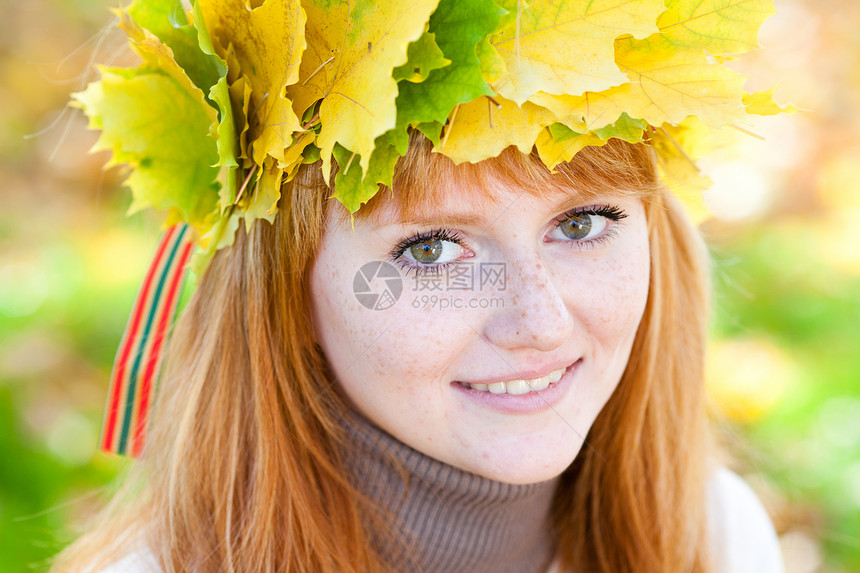 一位美丽的年轻红发女青年 在花圈的肖像金子学生成人叶子公园地面季节享受青少年森林图片