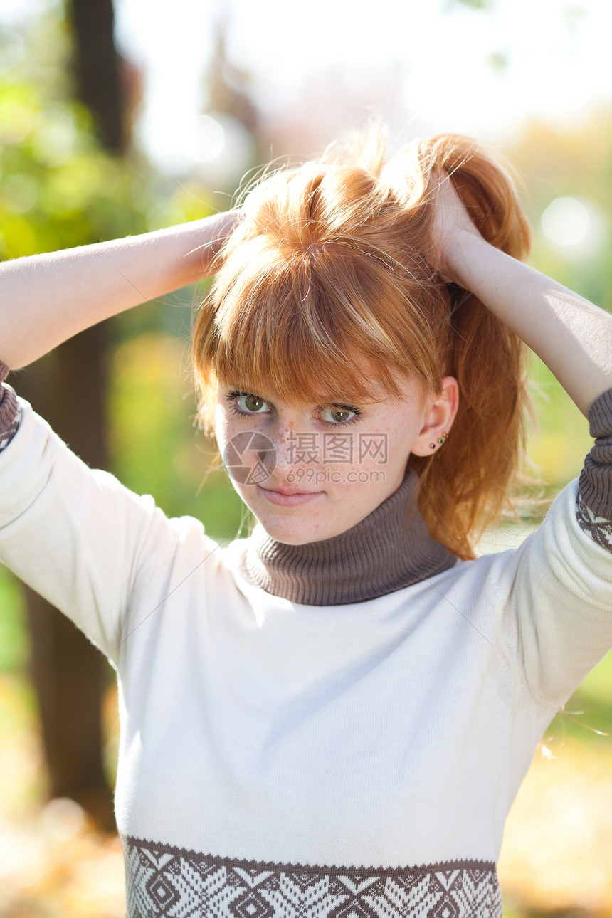 一位美丽的年轻红发女青年的肖像喜悦森林微笑地面头发女孩女性叶子公园乐趣图片