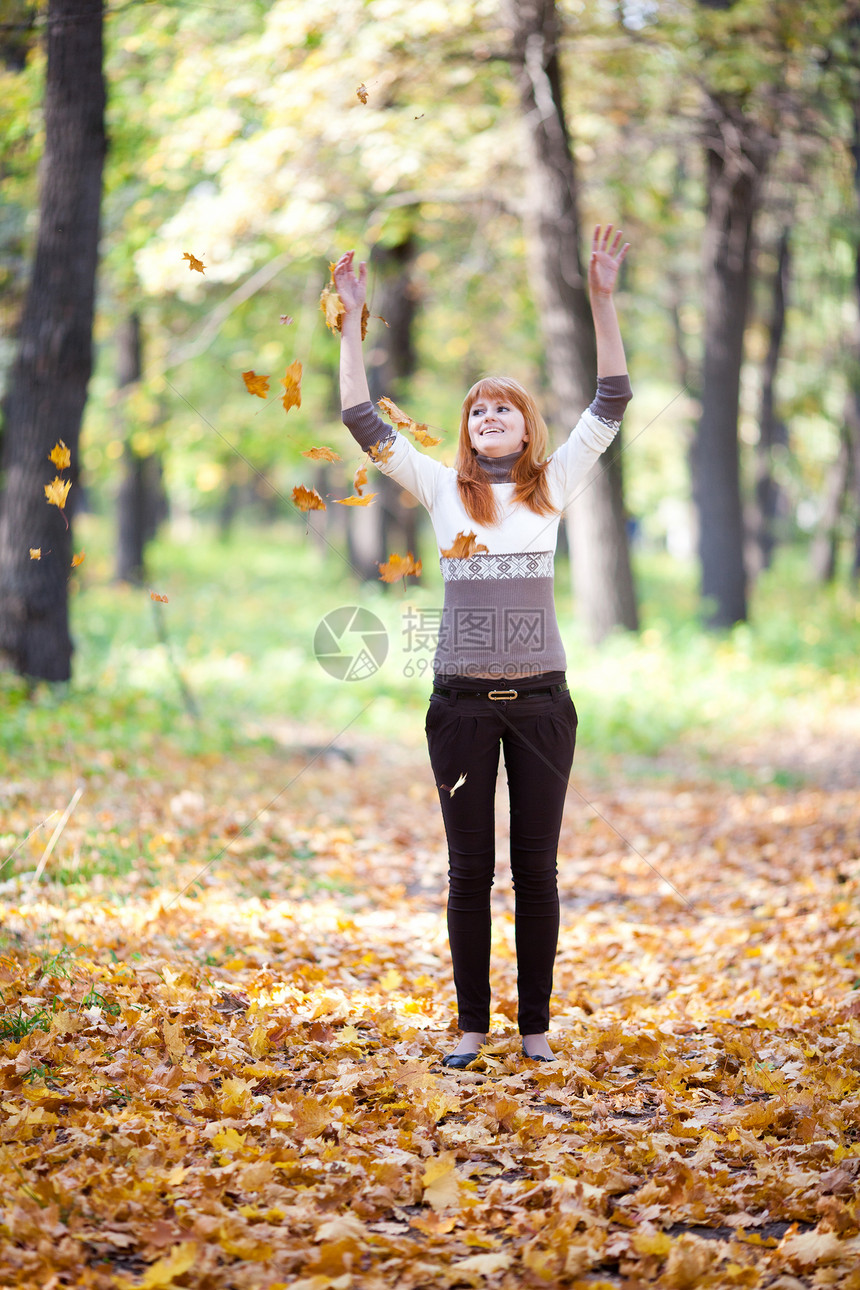 年轻红发青年青少年扔叶子 在森林中的女人金子公园跳跃幸福森林乐趣女性喜悦女孩季节图片