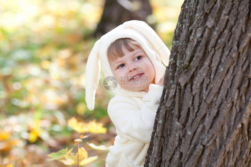 秋天森林中穿着装扮小兔子的漂亮女孩童年兔子女儿橙子喜悦毛皮乐趣叶子快乐微笑图片