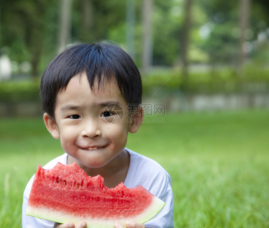 可爱的亚洲男孩 在草地上吃西瓜图片