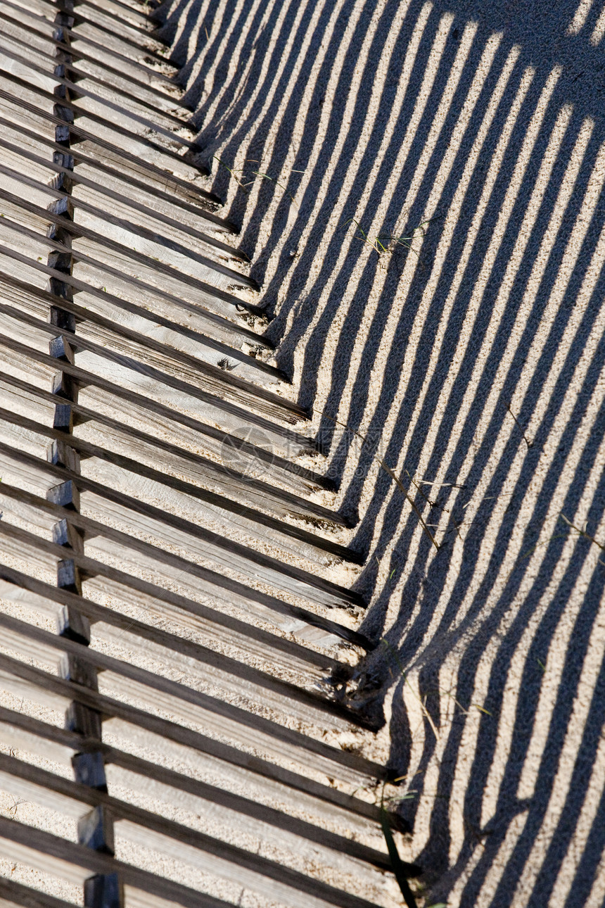 沙地上的栅栏线条木头阴影植被边界沙丘遮阳差距棕色黑色图片