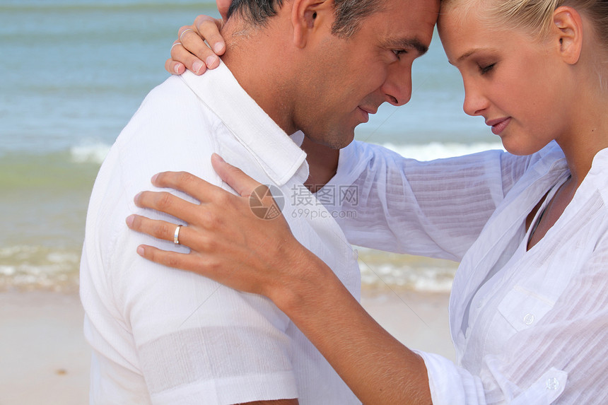 海滩上一对夫妇假期沙子蜂蜜眼睛脖子海岸男人拥抱太阳女士图片