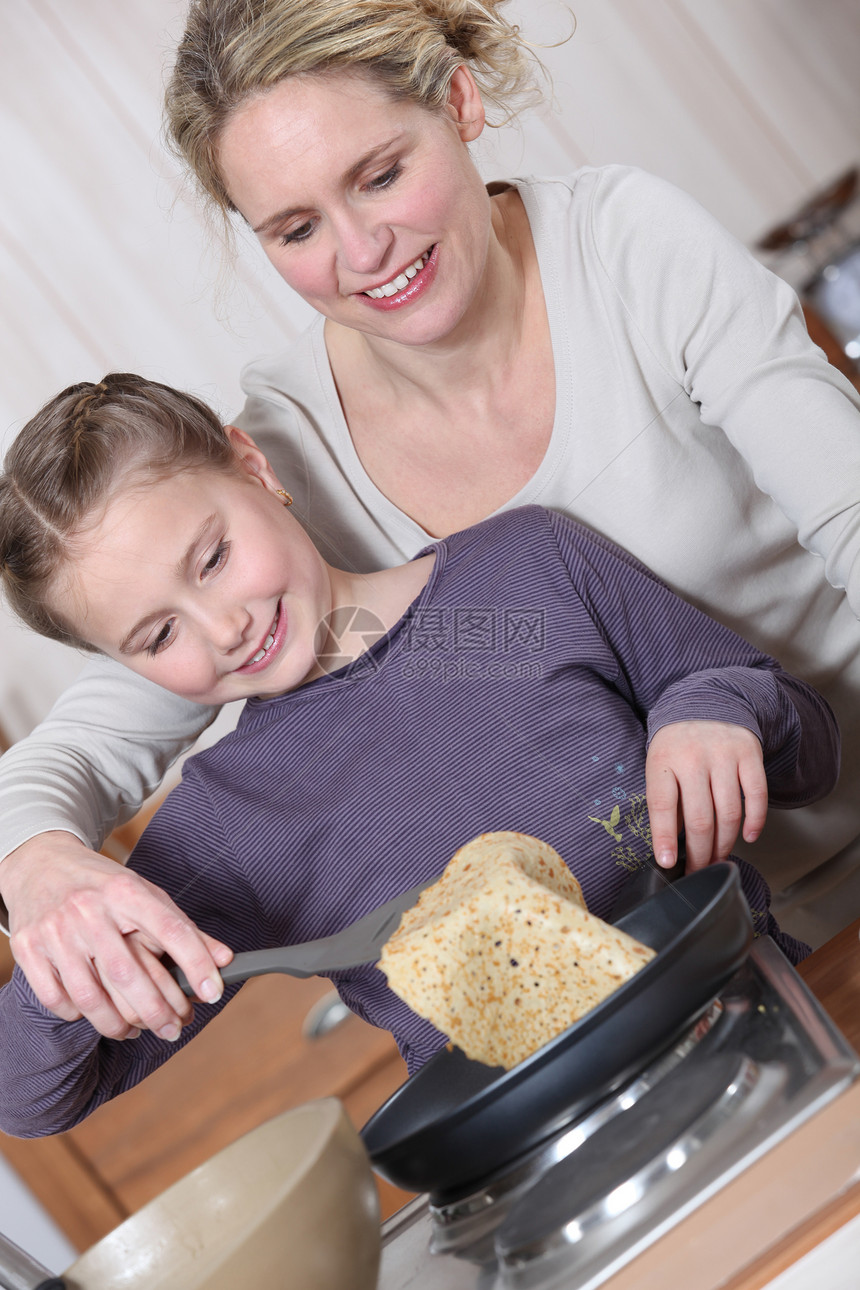 母亲和女儿做煎饼烹饪小吃糖浆饼子味道金黄色油炸甜点盘子育肥图片