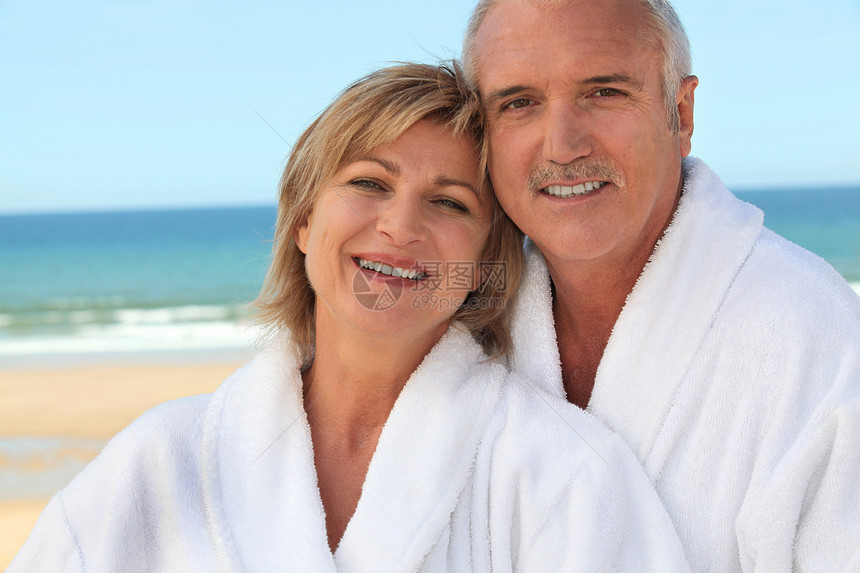 在浴袍海滩的一对夫妇图片