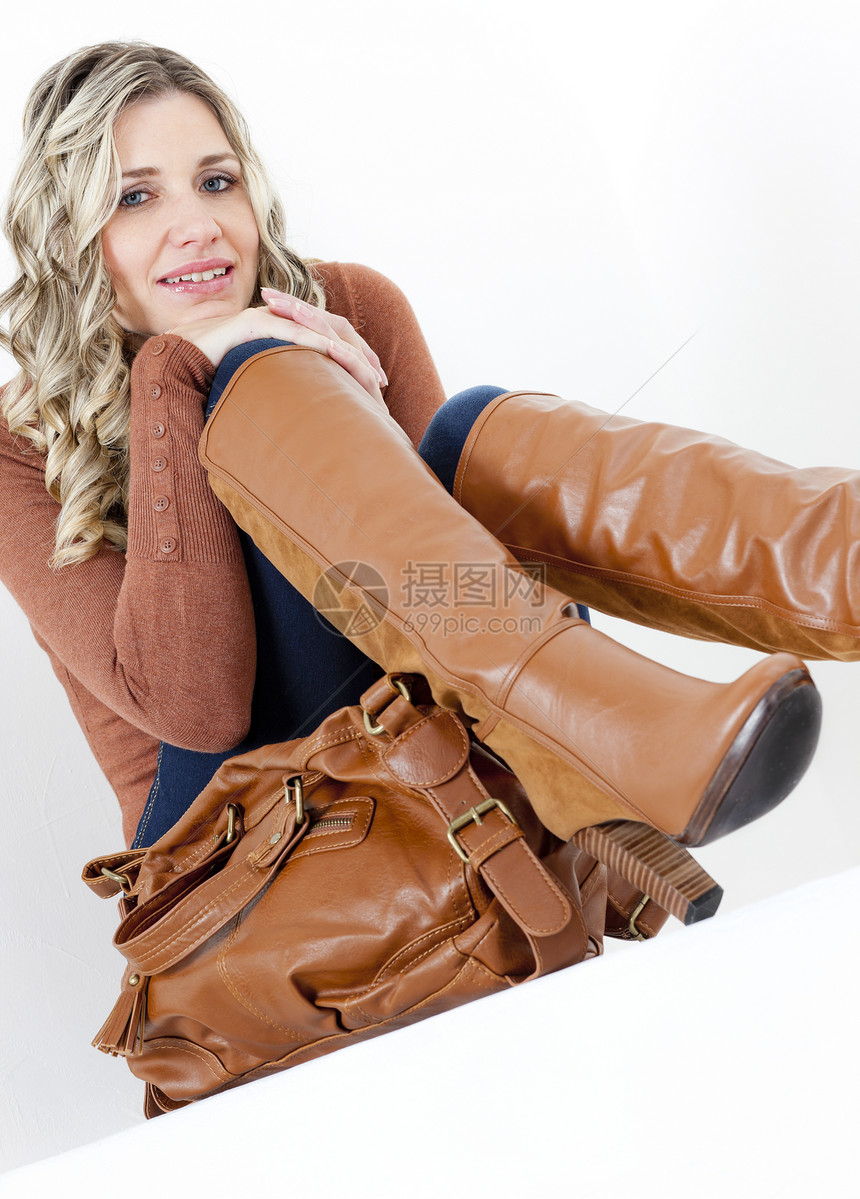 穿着时尚棕色靴子的女坐妇女肖像牛仔裤女士女性成人高跟鞋情绪微笑卷发金发情感图片