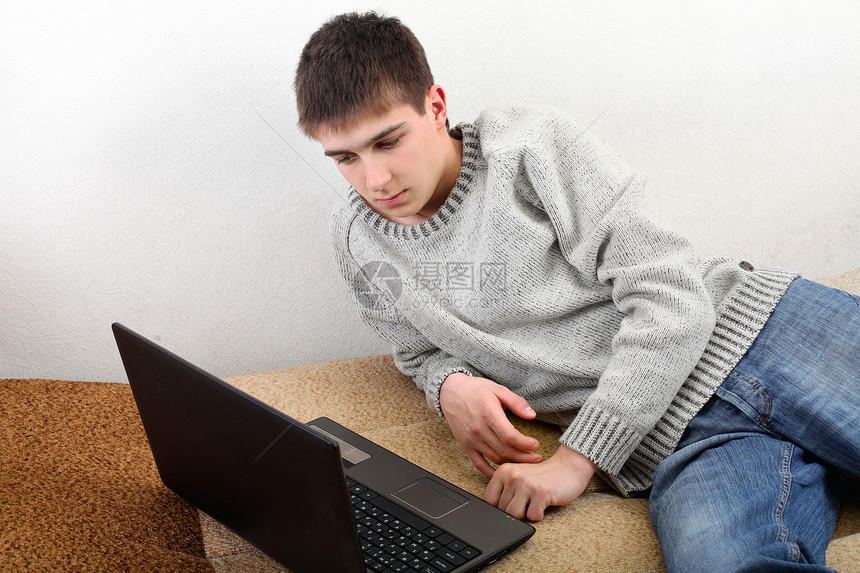 带笔记本的年轻人牛仔裤白色沙发毛衣键盘青年工具男生头发青少年图片