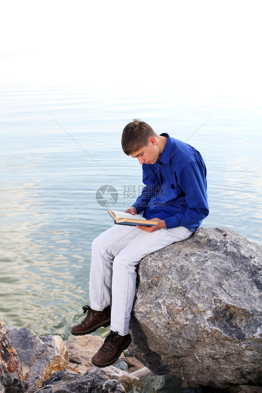 有书的青少年牛仔裤倾斜支撑海岸兴趣教育石头波浪头书学习图片