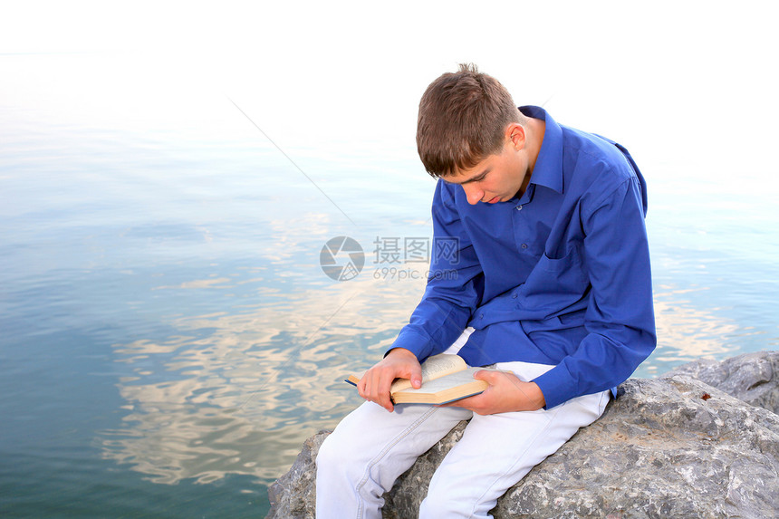 有书的青少年男性空闲岩石波浪牛仔裤海滨时间寂寞海滩头书图片