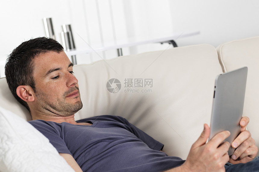 男人在沙发上青年软垫长椅男性电子幸福药片白色屏幕技术图片