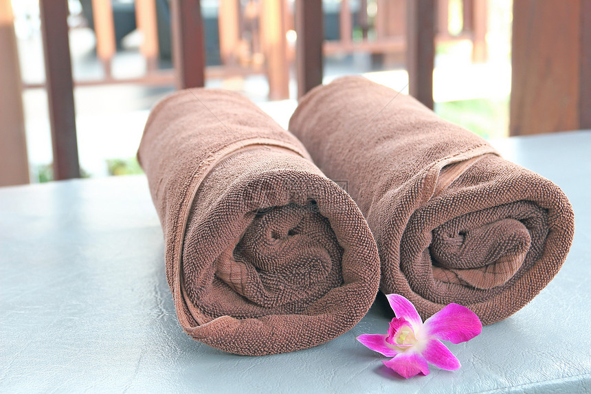 两条棕色毛巾卷在遮晒椅上图片