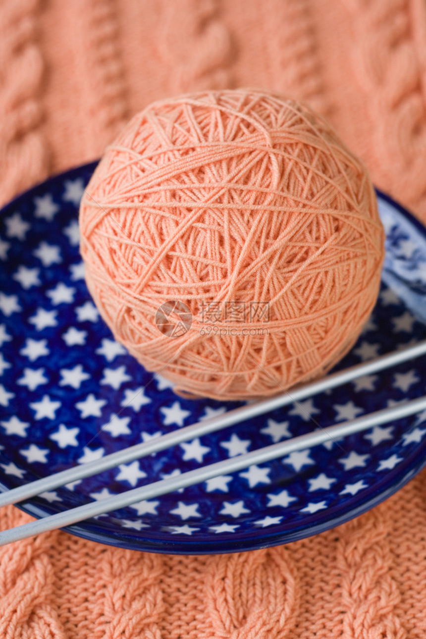 一球粉色线纹和编织针头 放在蓝色盘子上 有星号图片