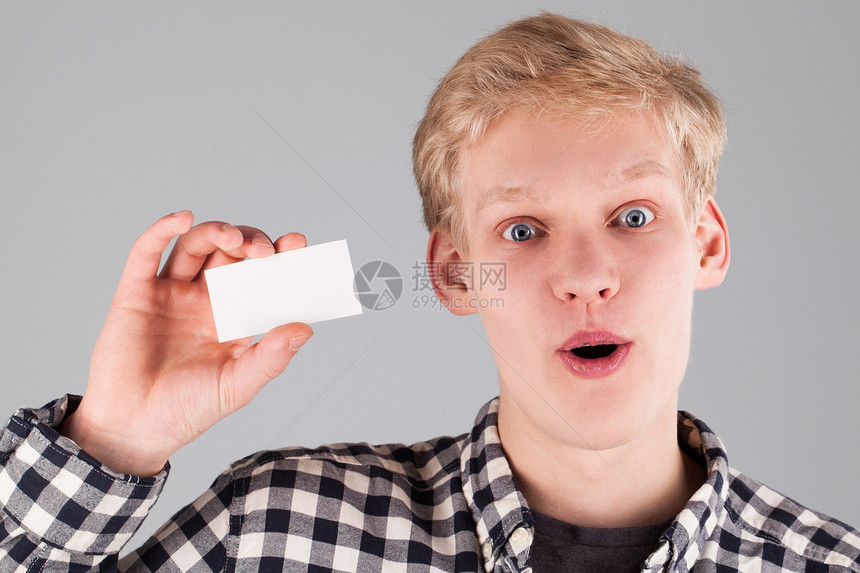 持有空白卡的英俊青年空白男人学生喜悦衬衫男性快乐白色名片工作室图片