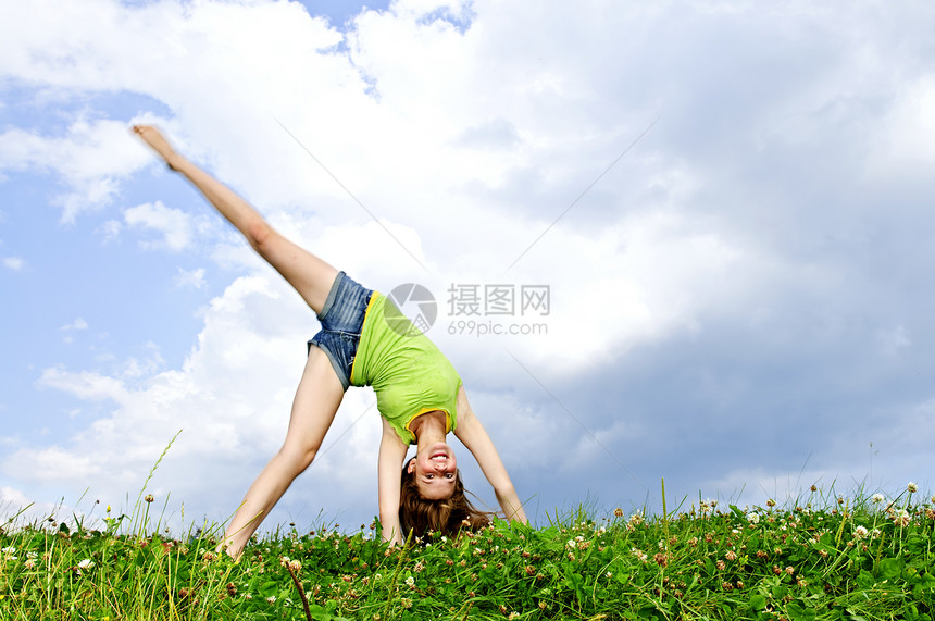 年轻女孩做手推车微笑乐趣女孩们赤脚场地侧手天空青少年草地体操图片