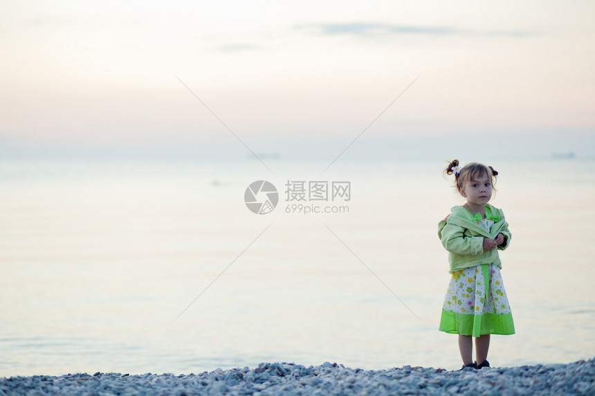 日落海滩上的孩子发型女性童年衣服裙子寂寞天空女孩卵石停留图片