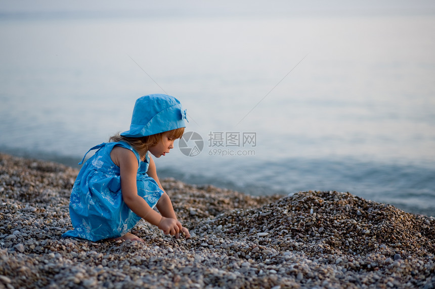 海滩上的小女孩日落童年快乐女儿帽子石头女孩孩子裙子赤脚图片