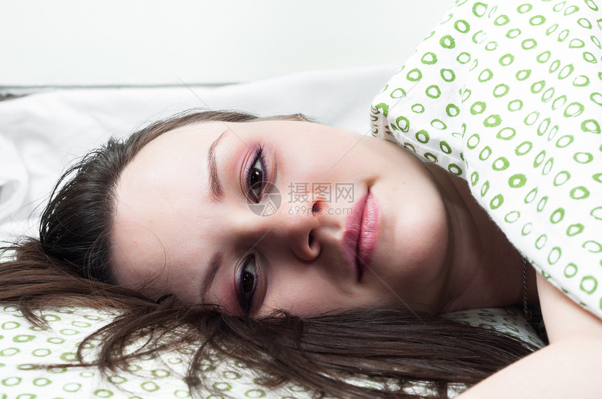 床上的年轻女人眼睛休息女士头发白色枕头女性卧室女孩图片
