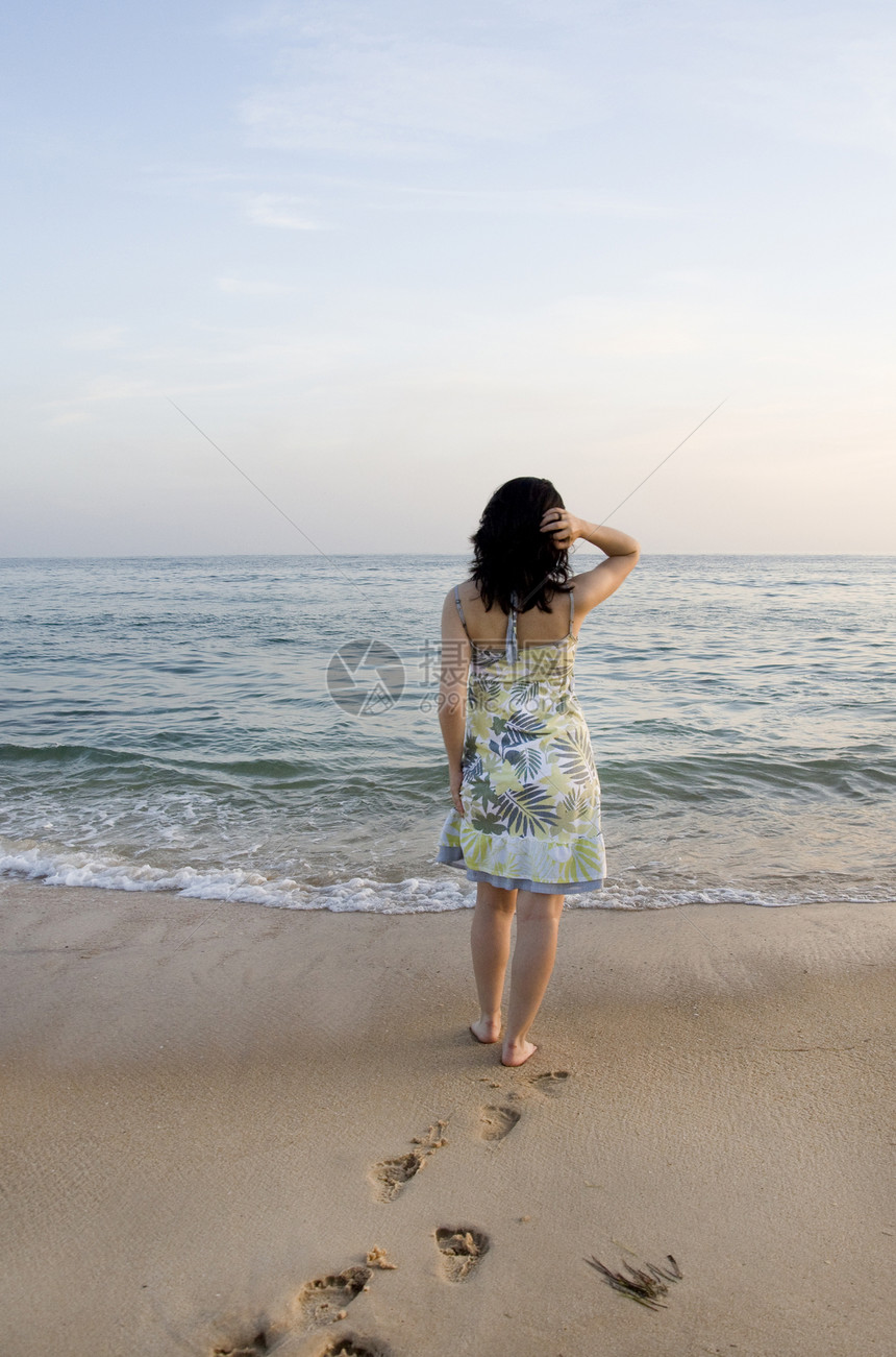 女人尝试水泡沫支撑女士旅行海浪地平线裙子海滩假期海岸图片