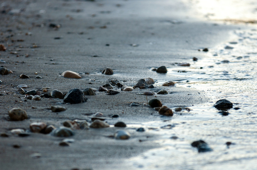 岸边的滑动石块卵石圆形日落美丽海浪海洋地平线岩石季节海岸线图片