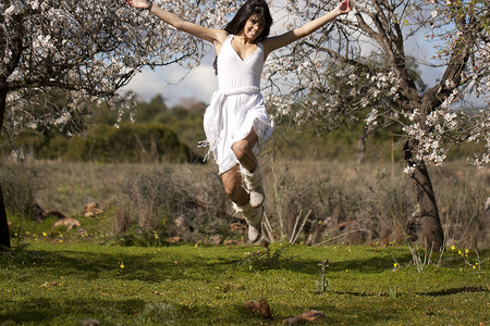 在纯白的绿地上场地裙子女孩喜悦冒充跳跃女士女性姿势头发背景图片