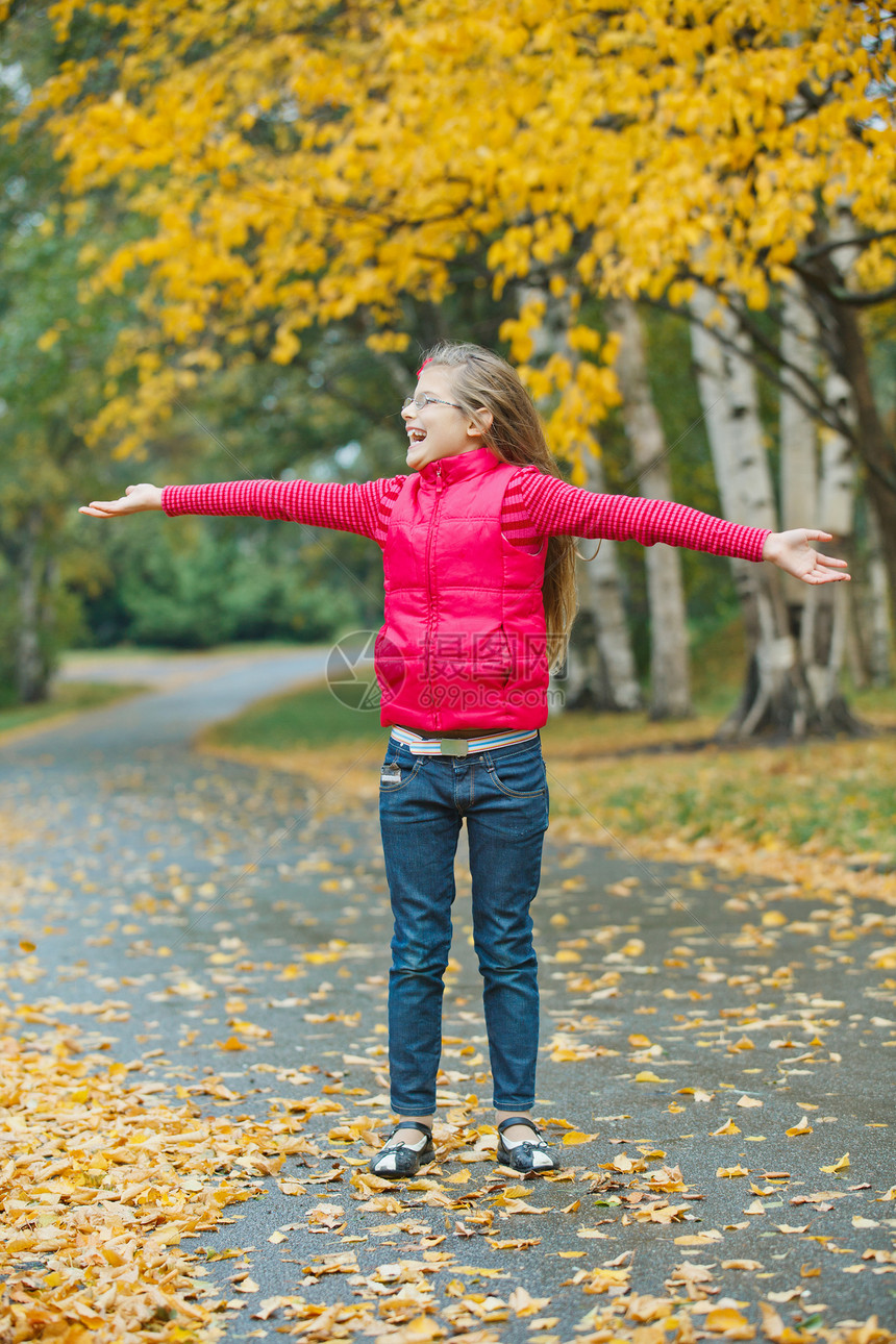 在秋天公园散步的可爱女孩童年微笑公园雨衣胡同闲暇女性青年快乐喜悦图片