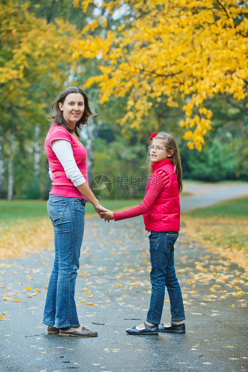 可爱的女孩和母亲在公园散步雨衣雨滴森林妈妈人行道闲暇女士天气胡同女性图片