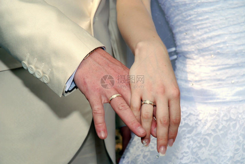 新郎和带戒指的新娘的手玫瑰婚礼白色花朵图片