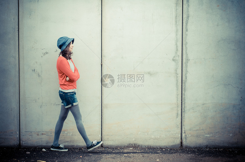 听音乐的漂亮时装女人街道衬衫短裤帽子音乐涂鸦耳机女孩城市玩家图片