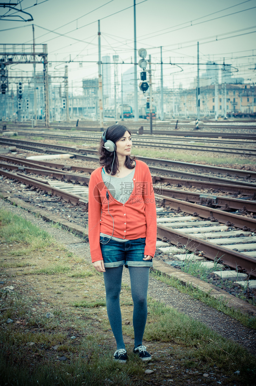 听音乐的漂亮时装女人玩家街道火车城市铁路旅行耳机车站短裤衬衫图片