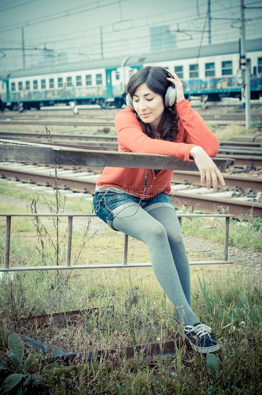 听音乐的漂亮时装女人铁路火车涂鸦耳机城市短裤衬衫旅行玩家车站图片