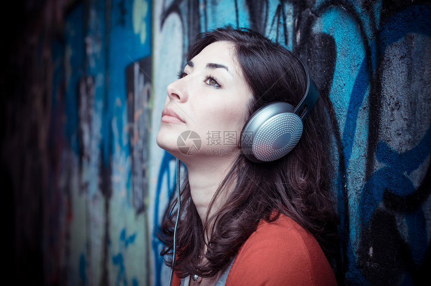 听音乐的漂亮时装女人城市音乐玩家说唱涂鸦耳机短裤女性衬衫街道图片