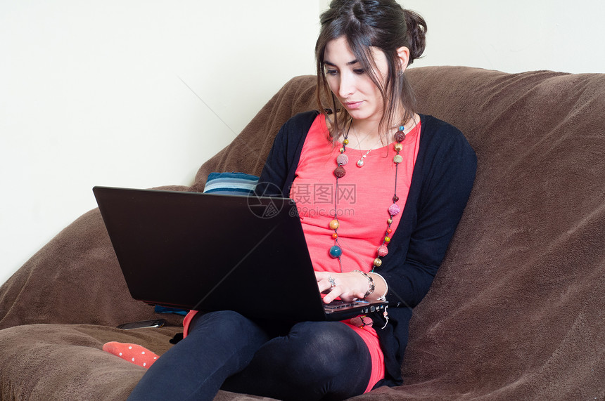 妇女在家里使用笔记本闲暇技术沙发女孩潮人电脑女士长椅女性黑发图片