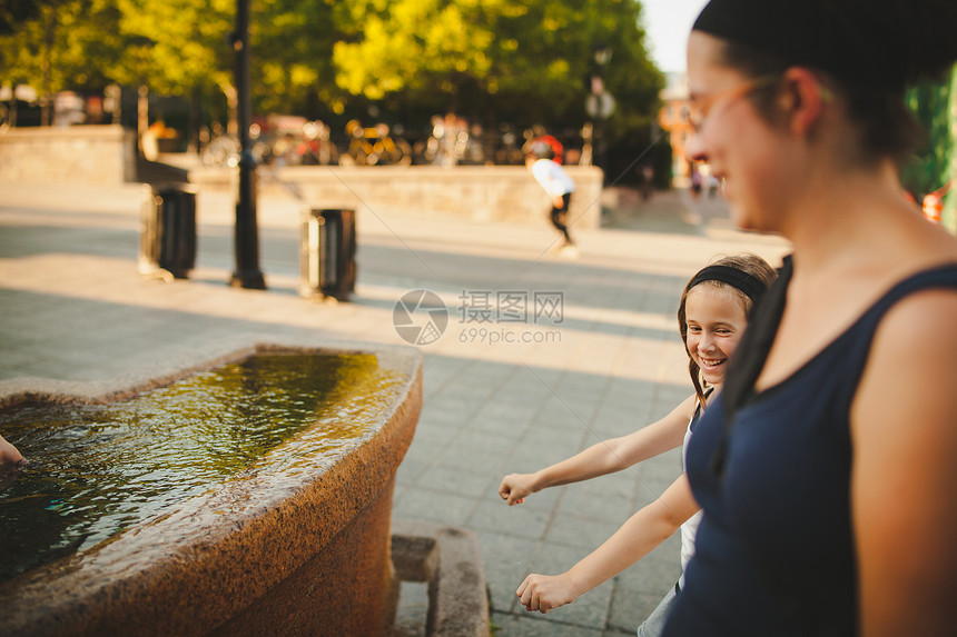 母亲和女儿在笑喷泉两个人成人乐趣孩子女士女孩微笑家庭城市图片