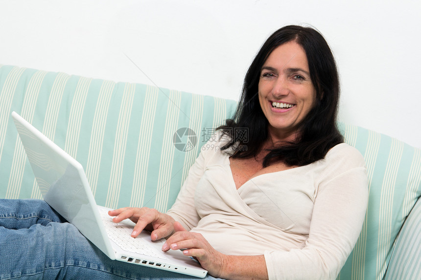 妇女使用笔记本电脑女士沙发喜悦工作乐趣技术互联网说谎冲浪长椅图片