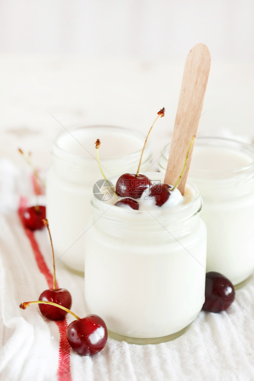 带樱桃的酸奶奶油勺子桌布瓶子牛奶香草液体食物水果玻璃图片