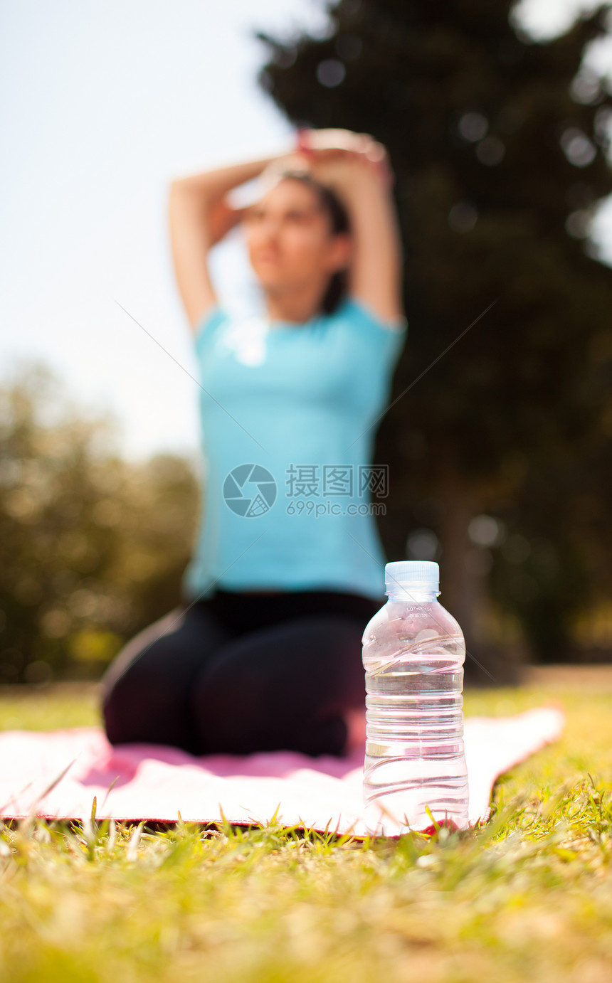 瓶装水 有妇女伸展在背景上女孩运动员女性蓝色训练活力森林微笑运动女士图片