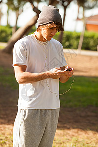英俊的年轻人在户外咨询电话音乐玩家邮件男人公园背景图片