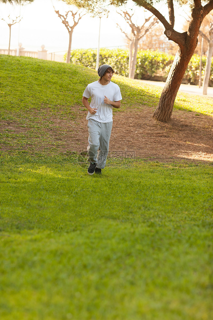 英俊的年轻人在公园里慢跑赛跑者白色锻炼慢跑者肌肉男人训练身体活力跑步图片