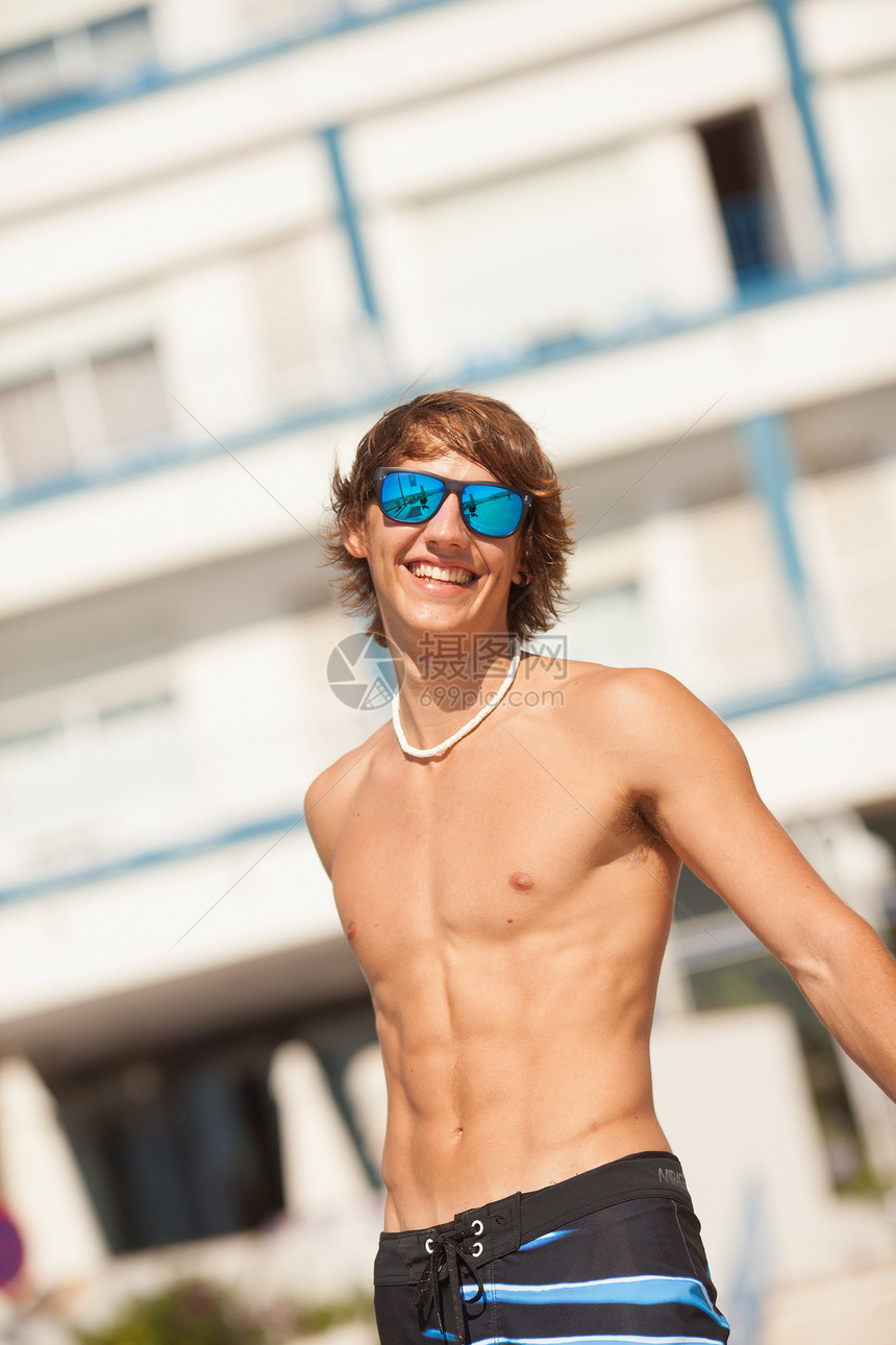 年轻健康的美丽男人 在海滩上欢笑的肖像乐趣绿色太阳眼镜运动海洋享受天空项链蓝色图片